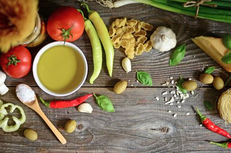 Italian and Mediterranean food ingredients on old wooden background. Spaghetti, olives, basil, cherry, tomato, pasta, garlic, pepper and oliveの写真素材