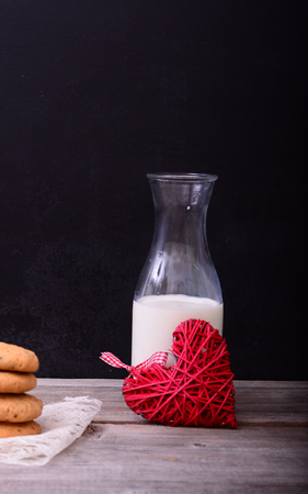 Stack of Chocolate chip cookies and bottle of milk on rustic tableの写真素材