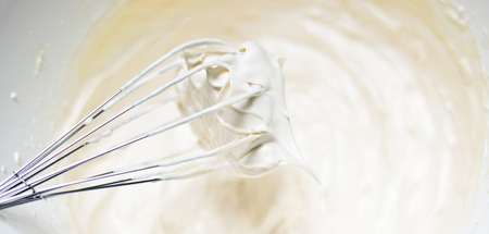 Whipping cream with a whisk close upの写真素材