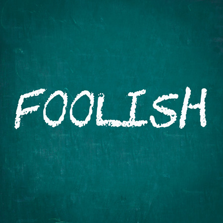 FOOLISH written on chalkboardの写真素材