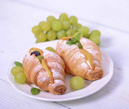 Fresh croissant with grapes on white backgroundの写真素材