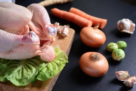Raw chicken with vegetables on black backgroundの写真素材