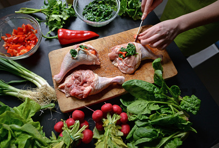 Young woman preparing chicken with vegetablesの写真素材