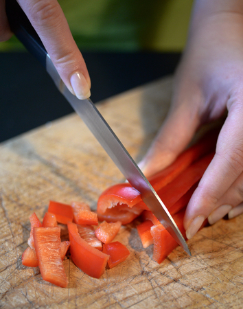 Female slicing pepper for salad. Close up chef cutting vegetables.の写真素材