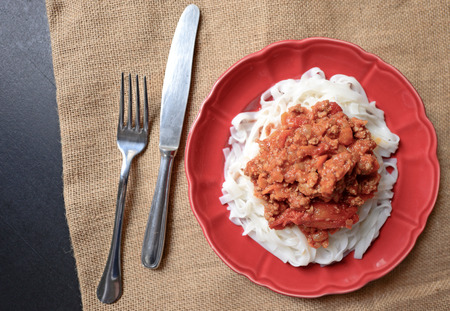 Italian spaghetti on red plate on tableの写真素材