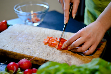 Female slicing pepper for salad. Close up chef cutting vegetables.の写真素材