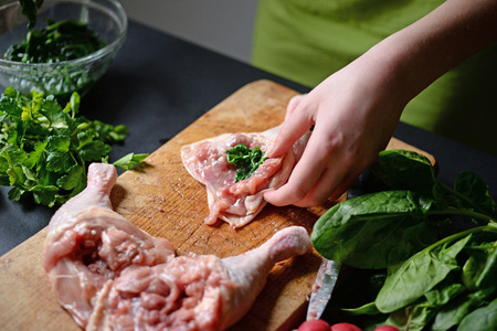 Young woman preparing chicken with vegetablesの写真素材