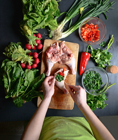 Young woman preparing chicken with vegetablesの写真素材