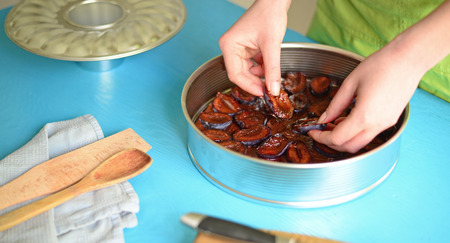 Woman preparing chocolate cake with plumsの写真素材