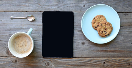 Tablet pc looking like ipad mini on table with coffee cupの写真素材