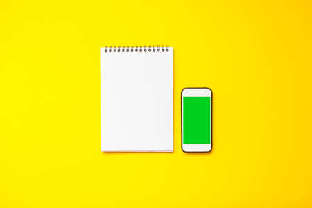 blank white sheet and smartphone on a bright yellow background. Mockupの写真素材
