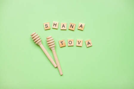 Words from wooden blocks "shana tova" and wooden spoons for honey on a green background. Rosh hashanahの写真素材