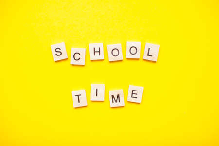 Words from wooden blocks "school time" on bright yellow backgroundの写真素材