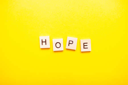 The inscription hope made of wooden blocks on a light yellow background.の写真素材