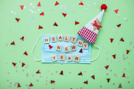 inscription from wooden blocks of a healthy new year on a medical protective mask and on a new year backgroundの写真素材