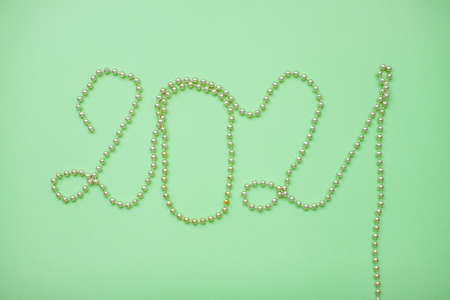 Happy New year 2021 celebration. Inscription 2021 from gold shiny new year beads on a green backgroundの写真素材