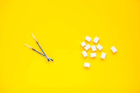 Compressed sugar cubes and insulin syringes on a yellow background. Diabetes.の写真素材