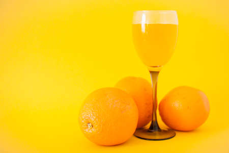 Bright oranges and a glass of orange juice on a bright yellow background. Healthy lifestyle concept. Vitamins and vigor.の写真素材