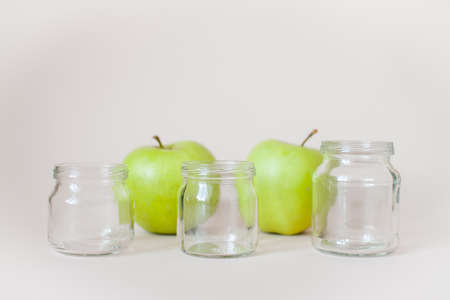 Green ripe apples and empty transparent jars for baby food on a light backgroundの写真素材