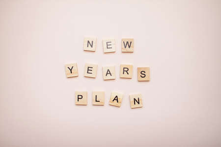 The inscription new years plan from wooden blocks on a light pink background.の写真素材