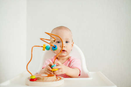 little girl plays with an educational maze toy. Development of fine motor skills and logical thinking. High quality photoの写真素材