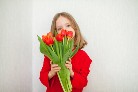 Beautiful girl in a bright red turtleneck holding a bouquet of red tulips. High quality photoの写真素材