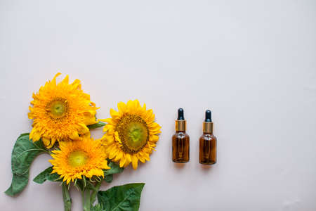 Flat lay of sunflowers and bottles for cosmetic serum or cream on a light pink background. The concept of beauty and preservation of youth. High quality photoの写真素材