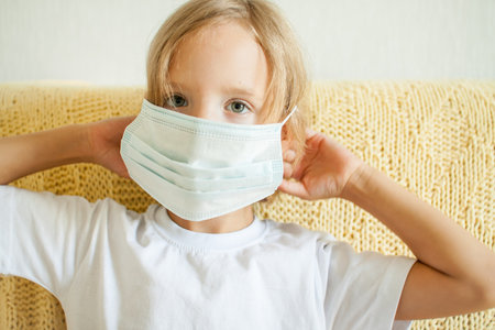 Portrait of a little girl putting on a medical protective mask. protection concept, quarantine. High quality photoの写真素材