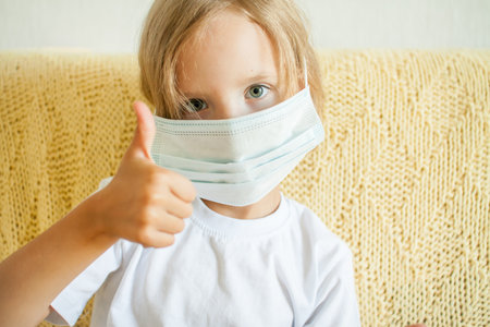 Portrait of a little girl putting on a medical protective mask. protection concept, quarantine. High quality photoの写真素材