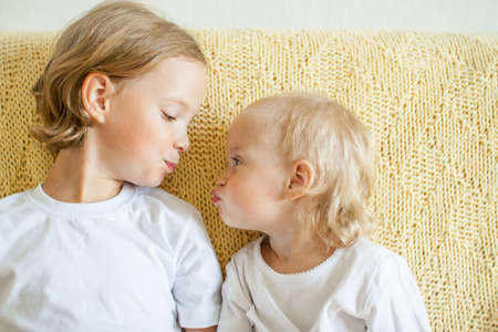 Portrait of two joyful happy sisters. The younger sister reaches out to kiss the older one. sisterly love. High quality photoの写真素材