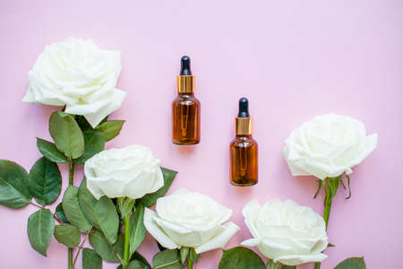 The layout of delicate roses and cosmetic bottles serum on a pink background. High quality photoの写真素材