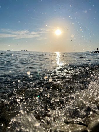 Sunlit ocean waves sparkling under clear blue sky with boats on horizon. High quality photoの写真素材