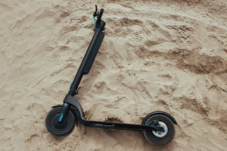 the electric scooter lies on the sand. ecology and movement concept