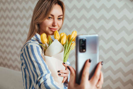 a beautiful woman takes a selfie with tulips .mother's day concept.の写真素材