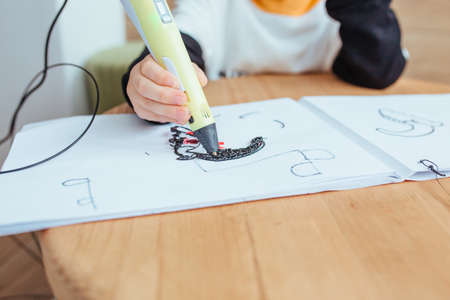 a child plays with a 3D pen. close up in the frame only the hands and the penの写真素材