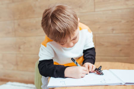 a fair-haired boy draws with a felt-tip pen. preparing for the school dayの写真素材