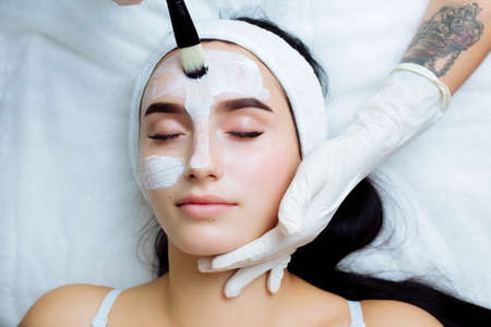 Facial cosmetic procedure in spa salon. The procedure for applying a mask to the face of a beautiful womanの写真素材