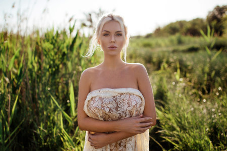 Sexy girl covered up in tulle in nature. body behind a piece of cloth. topless tan.