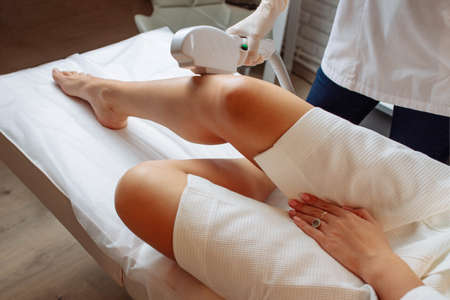 Young woman making body hair removal laser depilation in beauty centerの写真素材