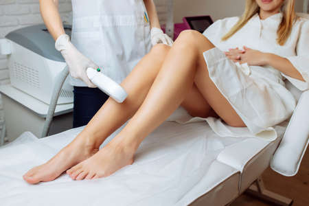Young woman making body hair removal laser depilation in beauty centerの写真素材