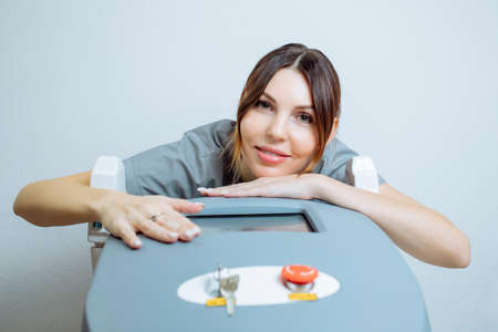 Female cosmetologist in a medical coat holds a working part of the modern laser epilator in her hands and poses for a photo. Laser epilation treatment in cosmetic beauty clinic.の写真素材