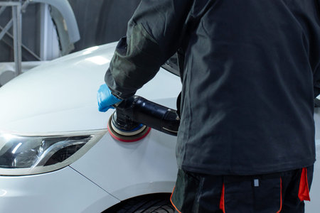 Serviceman polishing car body with machine in a workshop.の写真素材