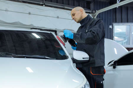 Serviceman polishing car body with machine in a workshop.の写真素材
