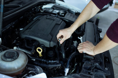 A male automech is inspecting the cars engine. Car service and car repair