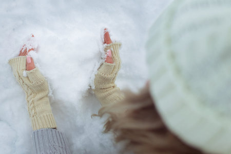 Close-up Snow heart in hands in knitted gloves on the background of snow cover. Valentines Day