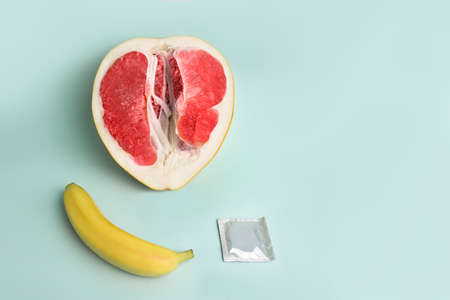 Safe sex. Juicy grapefruit and banana in a condom. The symbol of the vagina and penis from fruitの写真素材
