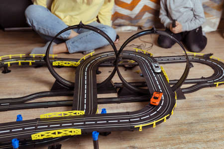 Mom and little son play racing on the carpet at home, have fun and hug. Single mother raises her son by playing carsの写真素材