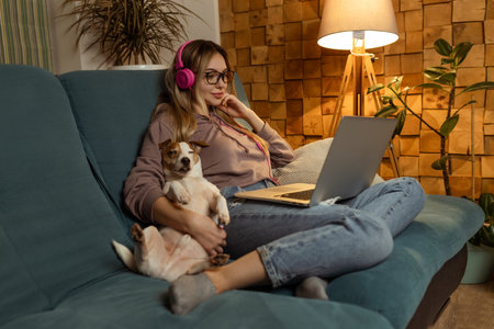A girl with a dog watching a movie on a laptop with headphones. Pets and pet friends for peopleの写真素材
