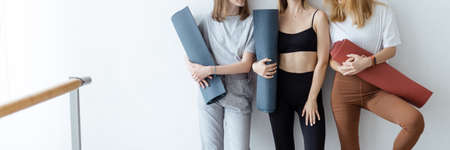 A group of young sports girls standing against a wall. time to recuperate, waiting for the start of the lesson in the loft studio, close-up. Healthy lifestyle conceptの写真素材