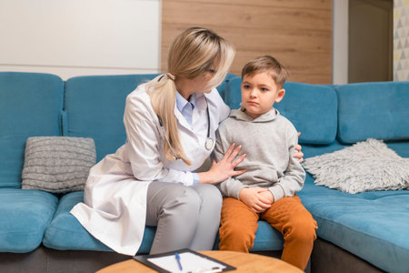 A family doctor examines a little boy at home. Pediatrician girl treats a childの写真素材
